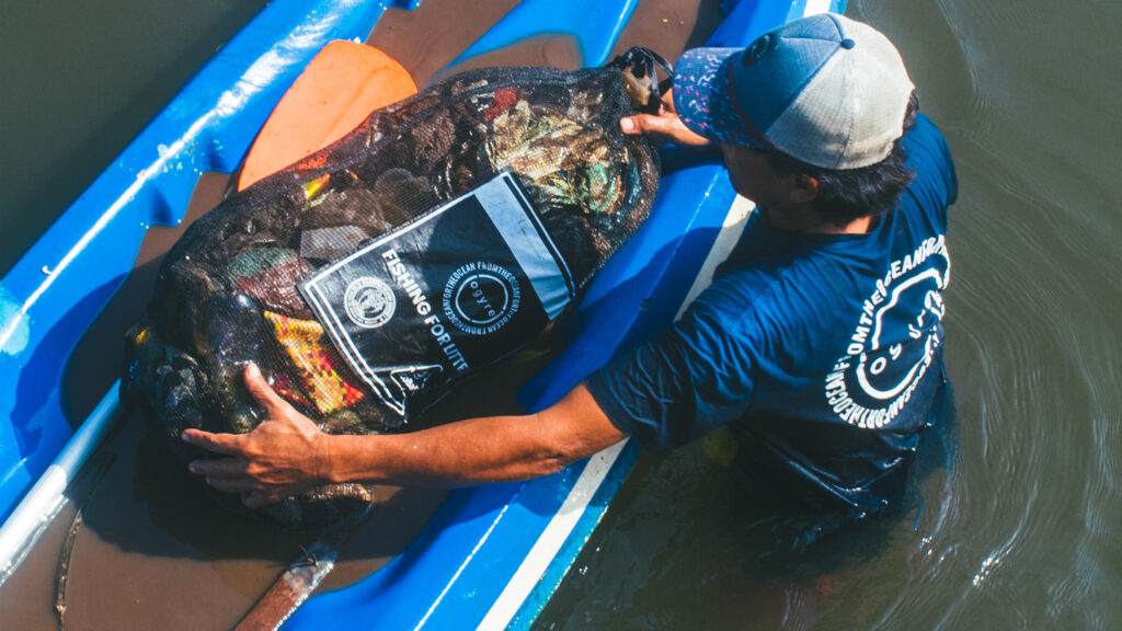 a man with bag of marine litter in fishing boat