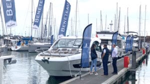 A pontoon with motorboats moored next to it. There are flags and some people. This is Ancasta's spring show on the Hamble