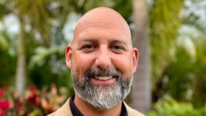 Middle aged man close up with palm trees blurred in background