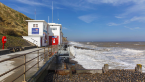 Small white RNLI station squats below a cliff in Sheringham North Norfolk