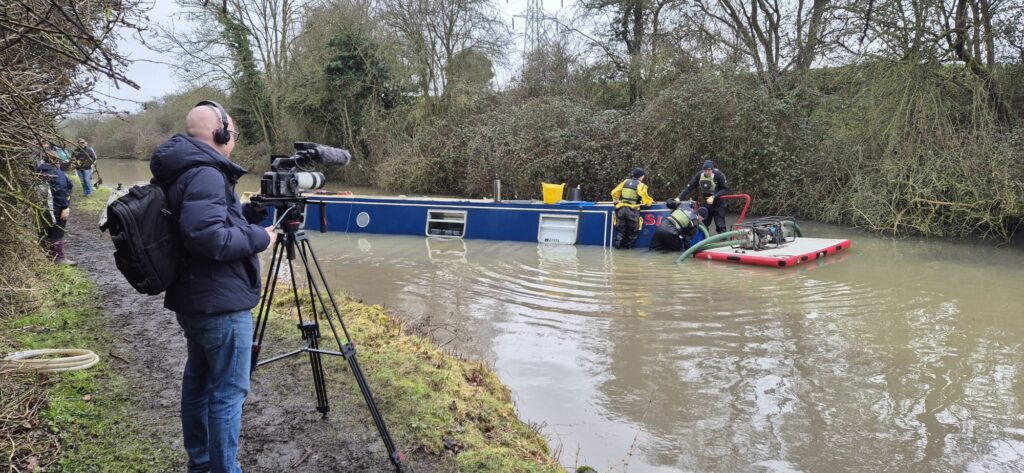 Narrowboat in water after being scuppered by thieves - process of raising starts with sealing up and pumping