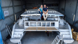 A couple sitting on an aluminum catamaran hull