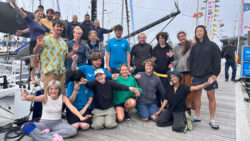 group of kids in front of a sailing yacht