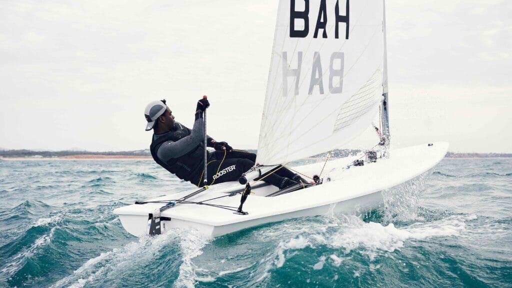 Sailor leans into the joy of his boat on water as he wears Rooster clothing