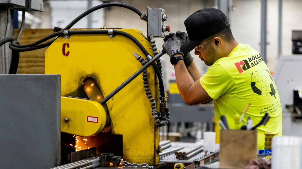man cuts steel bars in USA factory