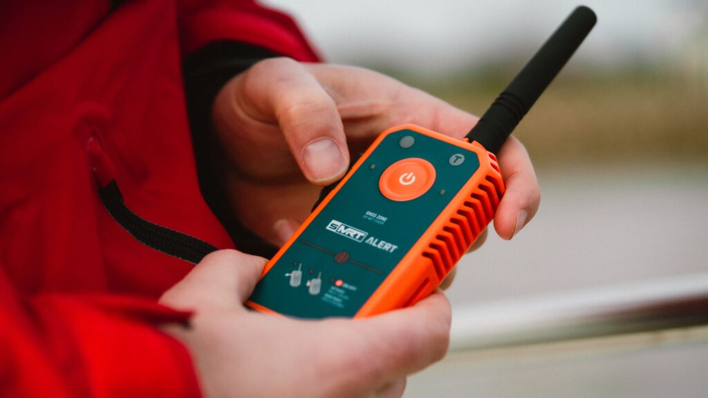 Orange man overboard handheld distress beacon in hands