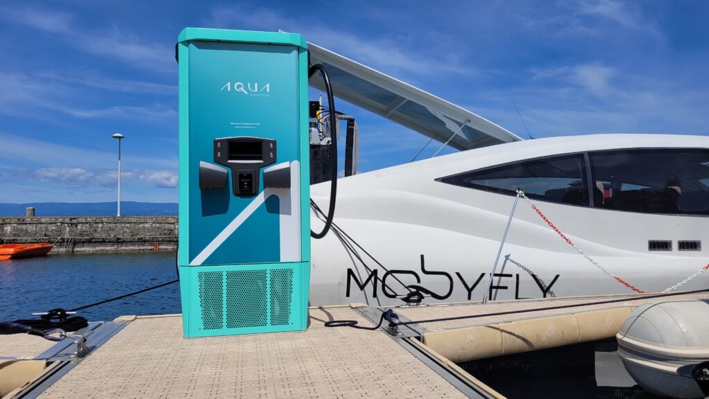 Aqua superPower electric charging station on pontoon in Lake Geneva with boat moored behind.