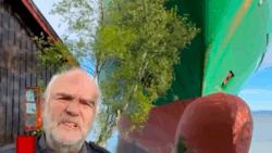 Man's head alongside containership in his front garden, Norway