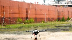 Drone on concrete in front of berthed containership as tests for shore-to-ship drone delivery take place