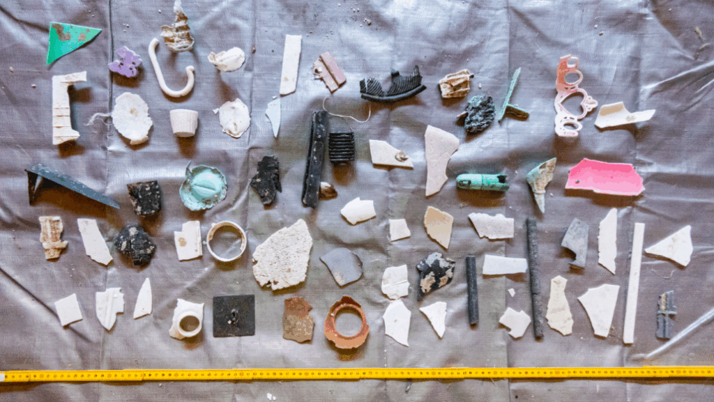Small pieces of hard plastic laid on a sheet next to a tape measure. These are collected by Ocean Cleanup from the Great Pacific Garbage Patch