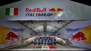 The Italy SailGP Team of Ruggero Tita, driver, Kyle Langford, wing trimmer, Andrea Tesei, flight controller, Enrico Voltolini, grinder, Alex Sinclair, grinder, Giulia Fava, strategist, and Matteo Celon, grinder of Italy SailGP Team, stand for a team photo in front of the Italy SailGP Team F50 catamaran and team hangar ahead of the Emirates Dubai Sail Grand Prix presented by P&O Marinas in Dubai, UAE. Wednesday 20 November 2024. Photo: Ricardo Pinto for SailGP. Handout image supplied by SailGP.