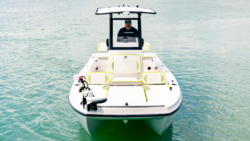 Front view of TwinVee boat designed for fishing with padded seats and centre console with one man standing