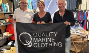three people holding a Quality Marine Clothing logo