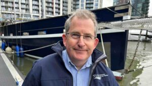 headshot of man by bow of large yacht