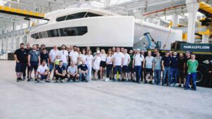 Group in front of white catamaran in factory