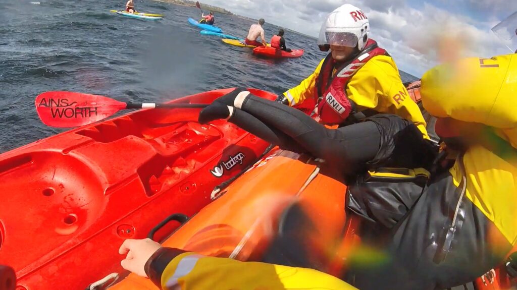 RNLI volunteers assisting a paddleboarder blown offshore