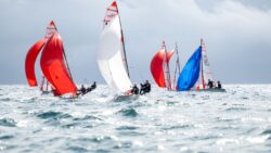 Red, white and blue dinghies sailors on the water