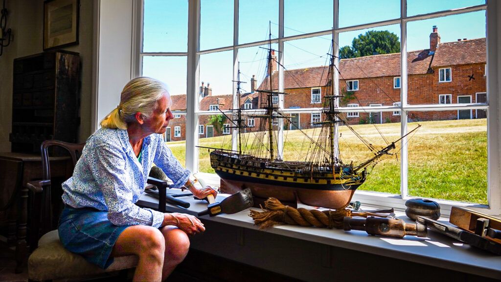 Mary Montagu-Scott looking at a model of a boat by window