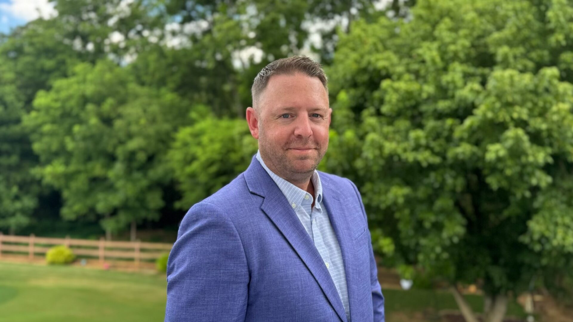 businessman in blue suit in front of trees