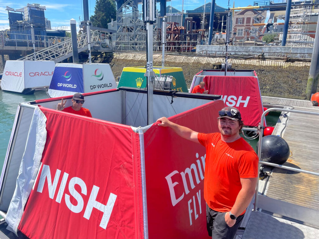 SailGP red finish race marker at Endeavour Quay with two people in red shirts
