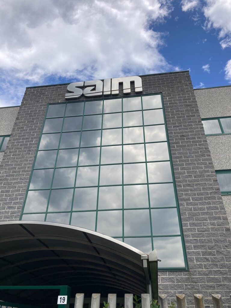 SAIM headquarters in Milan front entrance made of glass and reflecting clouds