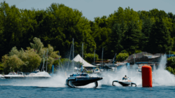 E1 boats race around a buoy with trees in the background