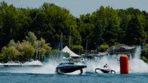 E1 boats race around a buoy with trees in the background