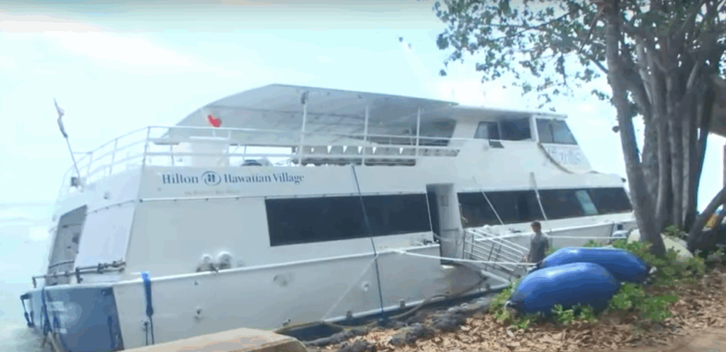 Honolulu ferry awaiting salvage against wall after accidental surfing incident grounds it