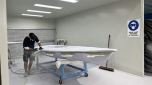 ILCA being made in Performance Marine Group premises Australia - worker in room with hull