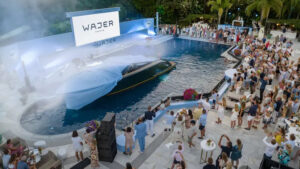 Wajer Yachts 44 being launched in a swimming pool as party goers look on dressed in their finery