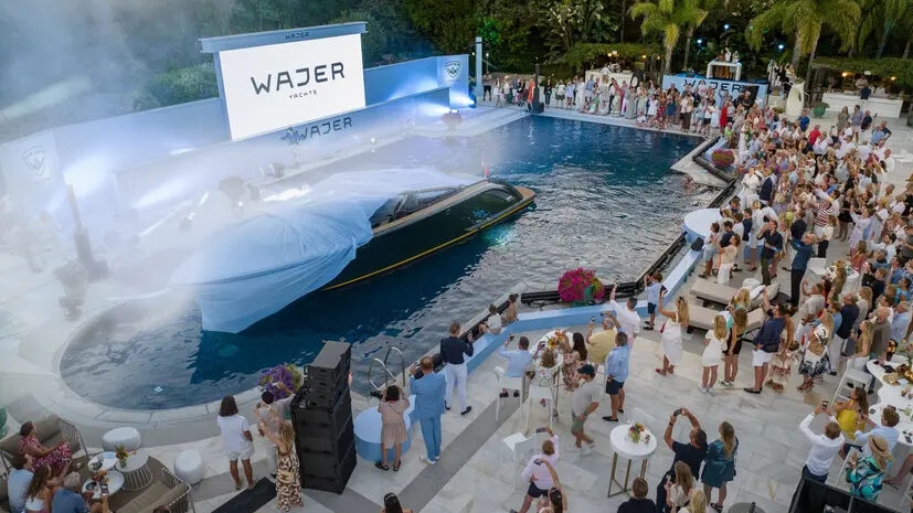 Wajer Yachts 44 being launched in a swimming pool as party goers look on dressed in their finery