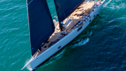 Aerial view of Wallywind 110 with black sails and crew perched along side
