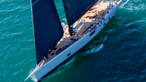 Aerial view of Wallywind 110 with black sails and crew perched along side