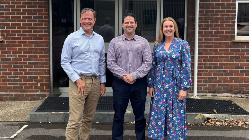 Zwei Männer und eine Frau stehen vor den Büros von Actisense, um die Beförderung von Justin Cohen bekannt zu geben