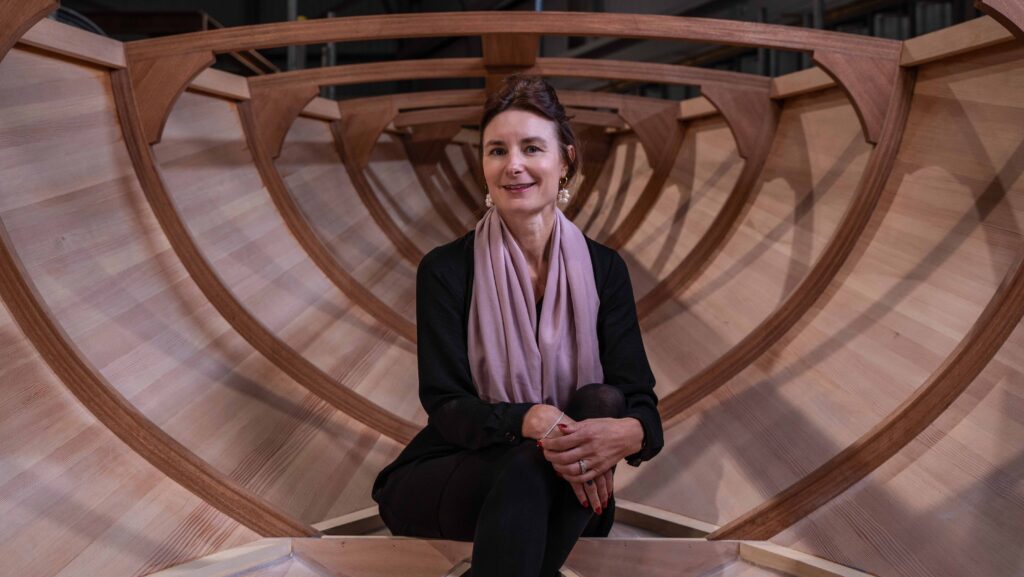 Karen Underwood sits inside the hull of a wooden Spirit Yacht