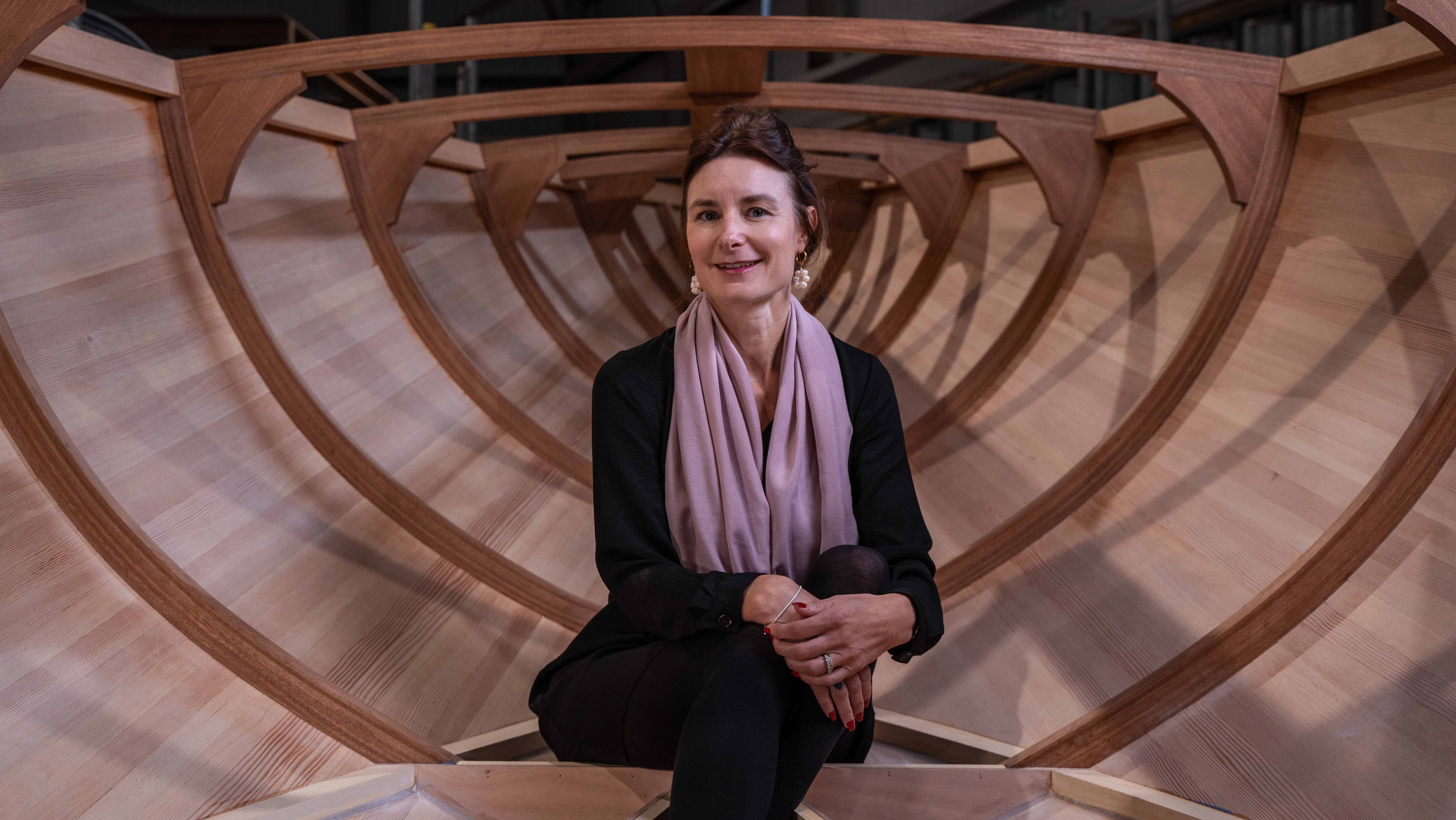 Karen Underwood sits inside the hull of a wooden Spirit Yacht