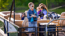 boy fishing off Lowe pontoon boat with family sat behind