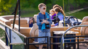 boy fishing off Lowe pontoon boat with family sat behind