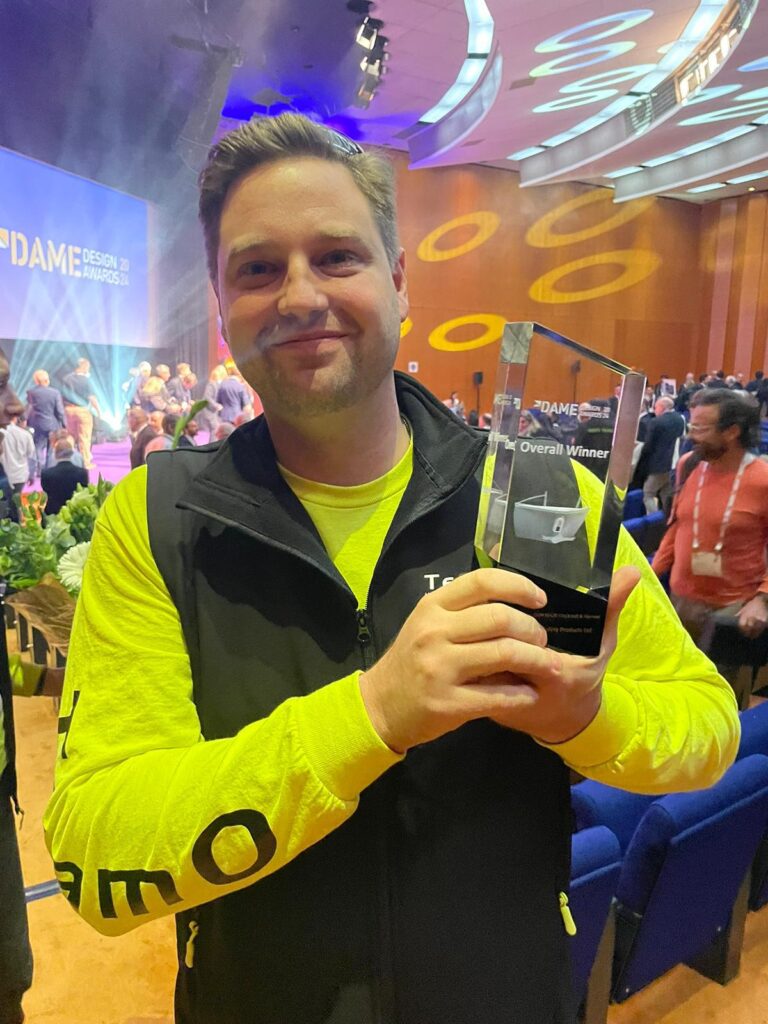 man in yellow top holding a trophy and smiling