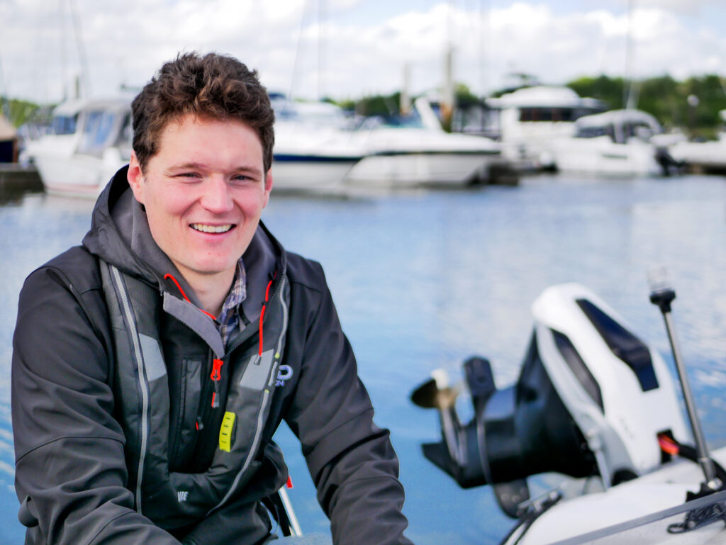Man on stern of dinghy with outboard