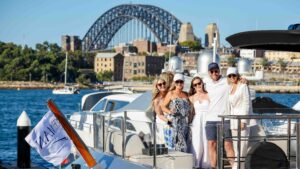 Small group of people smiling on superyacht with Sydney Harbour Bridge in background