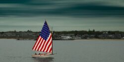 Sailing boat with US flag sails with Martha's Vineyard in the background