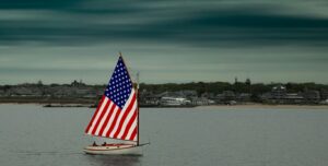 Sailing boat with US flag sails with Martha's Vineyard in the background