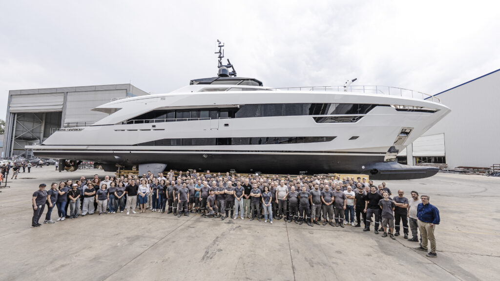 43m Alia Yachts white motor yacht side profile with group of people in the foreground