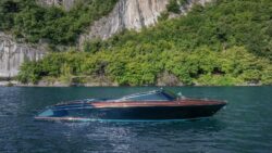 Riva boat on water in front of cliff
