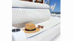 A bench seat on a boat with a hat and sunglasses. It's covered with Sumbrella's marine vinyl
