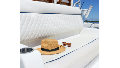 A bench seat on a boat with a hat and sunglasses. It's covered with Sumbrella's marine vinyl