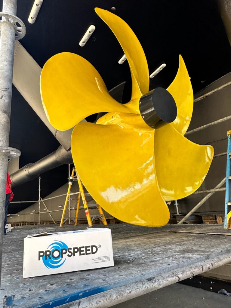 Bright yellow propellor under the hull in a shipyard