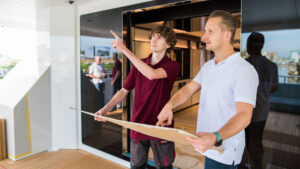 Two male workers look at diagram on boat stern