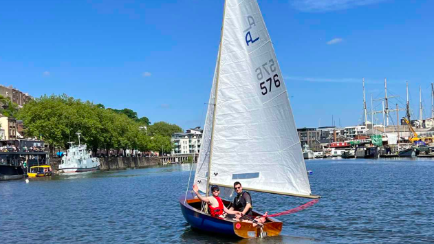 Two men in a boat with white sail